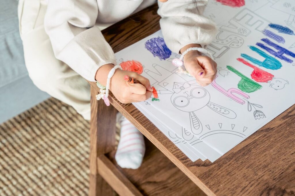 High angle of crop anonymous girl in bracelets painting picture with bright color for holy Easter